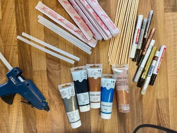 Überblick über die Materialien zum Zauberstab basteln im DIY mit Heißklebepistole, Acrylfarben, Stäbchen, Acrylstifte