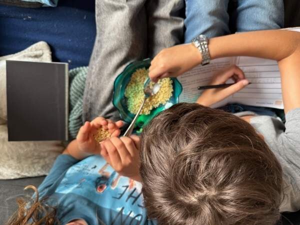 Kinder, die gerade aus der "Wahrsageschüssel" mit ganz vielen Suppenbuchstaben, einzelne Buchstaben heraus suchen