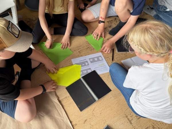 Kinde,r di um die Anleitung zum Papierflieger setzen mit buntem Papier in der Hand
