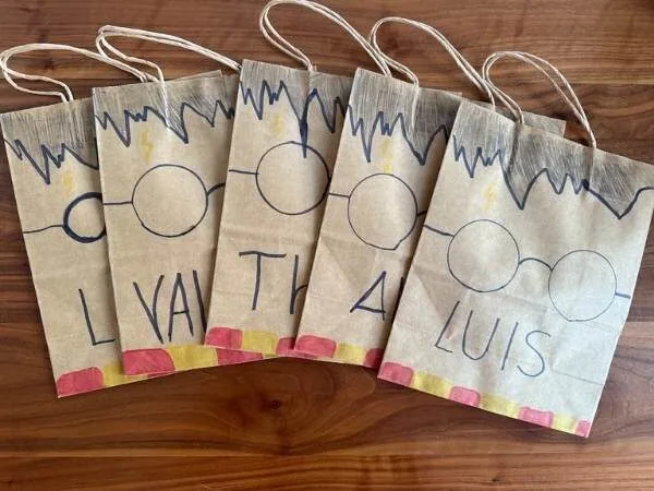 Bunte selbstgemachte Geschenktüten mit handgeschriebenen Namen und kinderfreundlichem Design, ideal für Geburtstagsfeiern und kreative Kinderfeste.