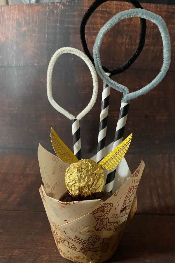 Muffin mit einem Ferrero Rocher mit Flügeln und 3 Pfeifenputzern als Ringe