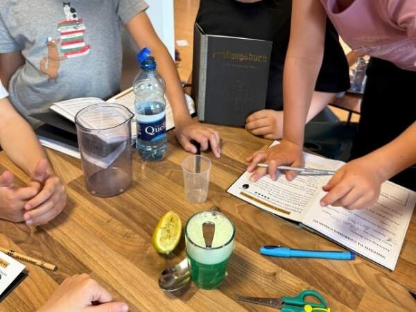 Ein Tisch mit einem Zaubertrank und Kindern mit Büchern, die gerade was eintragen