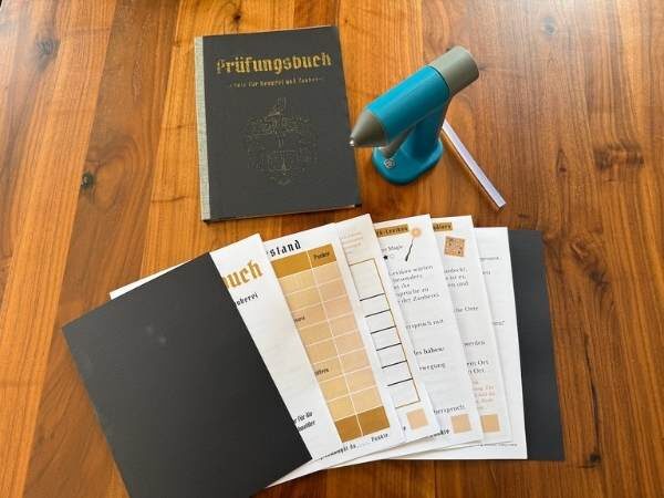 Prüfungsbuch geschlossen und die einzelnen Teile des Buches und eine Heißklebepistole