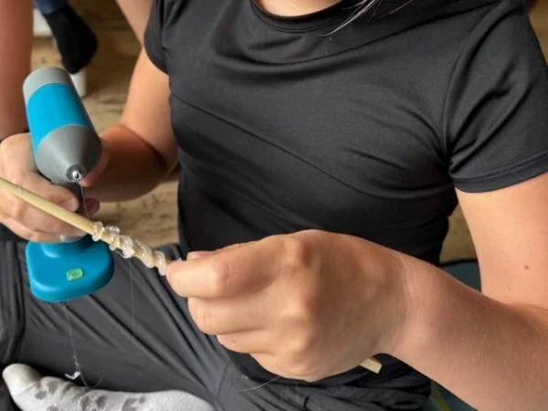 Kind macht mit Heißklebepistole gerade die Strukturierung auf den Stab