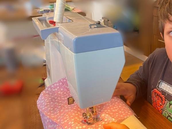 Nähen mit einer Nähmaschine, Kind beim kreativen Basteln, Heimarbeit und Handarbeit, kreative Beschäftigung für Kinder, Nähprojekt im Kinderzimmer, Mama-Blog-Thema, Nähmaschine und Stoff, DIY Kindermode, Handarbeit für Kinder, Handwärmer selber nähen