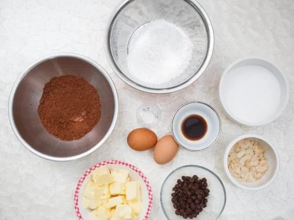 Zutaten für Schokoladenkuchen: Kakaopulver, Eier, Butter, Zucker, Milch, Vanille, Schokoladenstückchen, Backpulver, Salz. Perfekt für köstliches Gebäck.