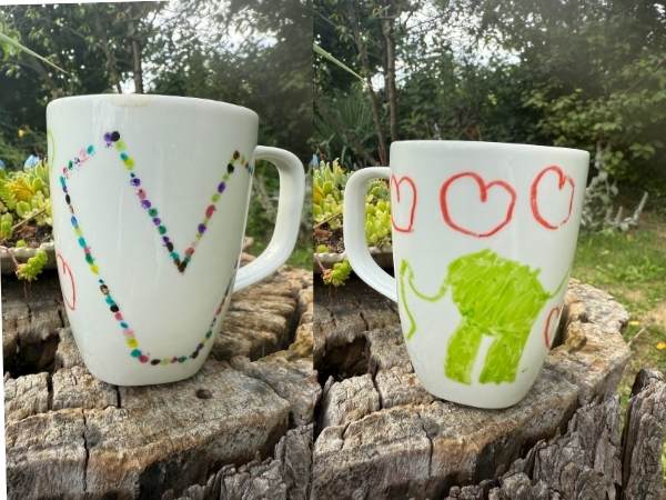 Bunte handgemalte Tassen mit Kinderzeichnungen auf Baumstamm im Garten, ideal für Mama und Kinder, kreative Geschenke, schöne Muttertagsideen, für liebevolle Momente mit der Familie.