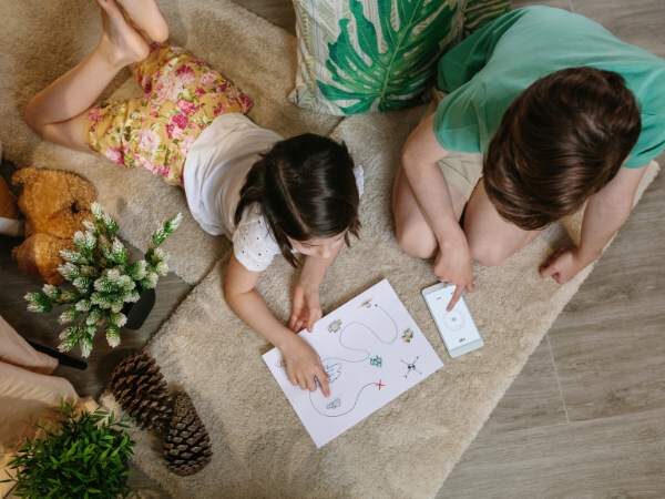 Bilder von Mutter und Tochter beim kreativen Spiel mit Mal- und Zeichenmaterialien auf einem ruhigen, gemütlichen Wohnzimmerteppich.