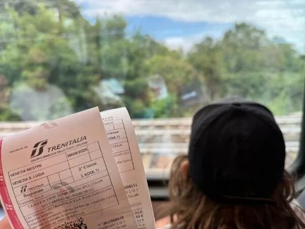 Kopf von Kind, das aus dem Zugfenster schaut und daneben die zwei Zugtickets