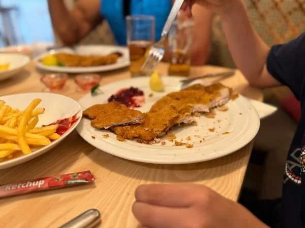 Frittierte Schnitzel auf einem Teller mit Pommes und Ketchup beim Essen im Restaurant.