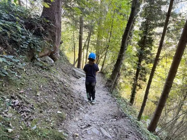 Pfad im Wald mit Kind in Helm, Naturerlebnis, Familienausflug, Abenteuer draußen, Waldwanderung für Kinder.