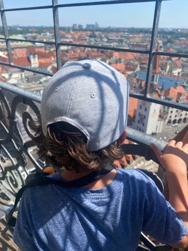 Kind von hinten, wie es von einem Turm auf München schaut