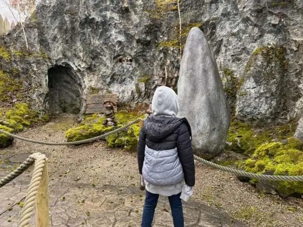 Stehende Frau vor einer großen Steinskulptur im Naturlandschaft, erkundet einen faszinierenden Ort, ideal für einen Familienausflug oder Naturerkundung in Österreich.