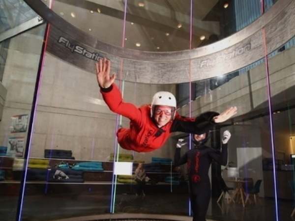 Frau fliegt im Windkanal von Bodyfly im roten Anzug mit Helm