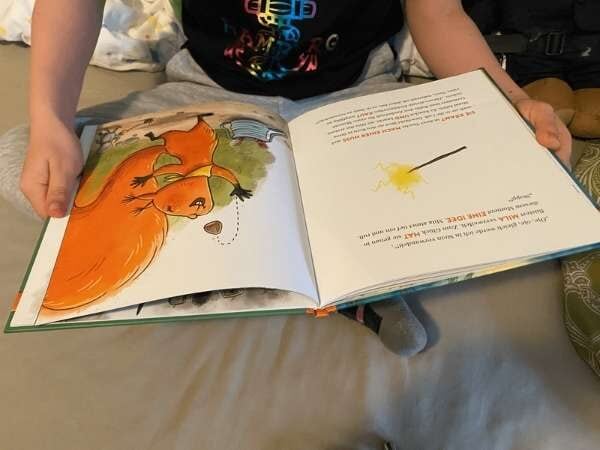 Bilder von einem Kind beim Vorlesen eines Bilderbuchs mit Tierillustrationen, gemütliche Atmosphäre, ideal für Eltern-Kind-Lesezeit.