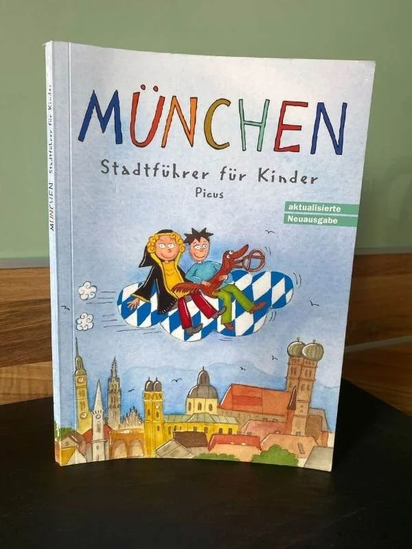 Ein Buch mit dem Cover und dem Titel "München - Stadtführer für Kinder" und einer Zeichnung von München auf dem Cover