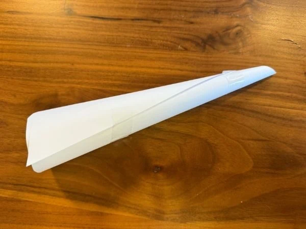 Horn aus weißem Papier mit Klebestreifen fixiert auf einem Holztisch liegend