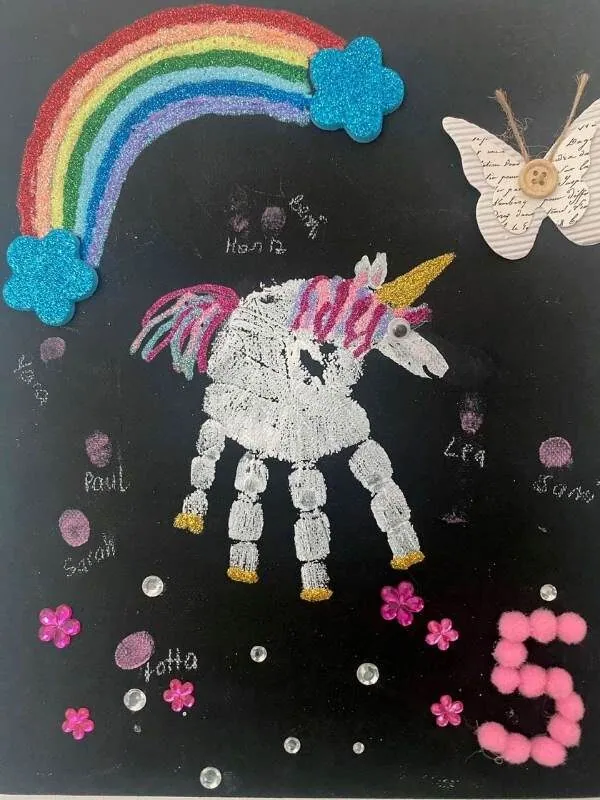 -leuchtende Regenbogen mit Wolken und Einhorn aus Glitzer- und Bastelmaterial, fantasievolles Kinderkunstwerk, kreative Bastelidee für Kinderzimmerdekoration.