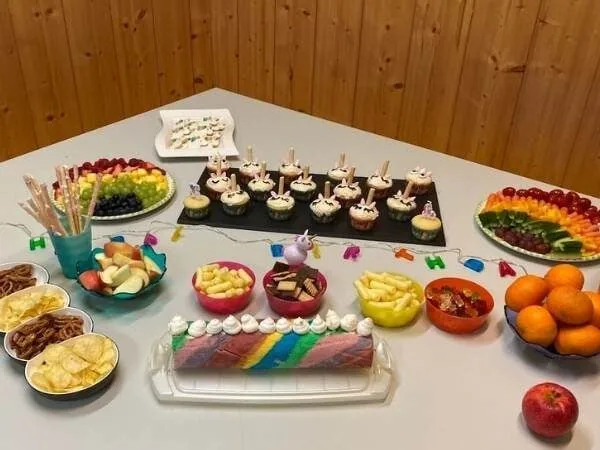 Bunte Kindergeburtstagsdeko mit Kuchen, Cupcakes und frischem Obst, perfekt für eine Einhorn Party im Elternhaus.