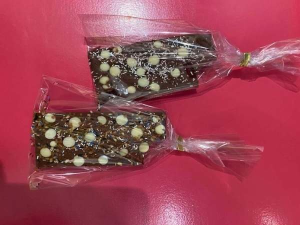 Leckere Schokoriegel mit weißer Schokolade in transparenten Verpackungen, perfekt für Naschkatzen, glutenfrei und mit hochwertigen Zutaten, ideal als Geschenk oder Snack.