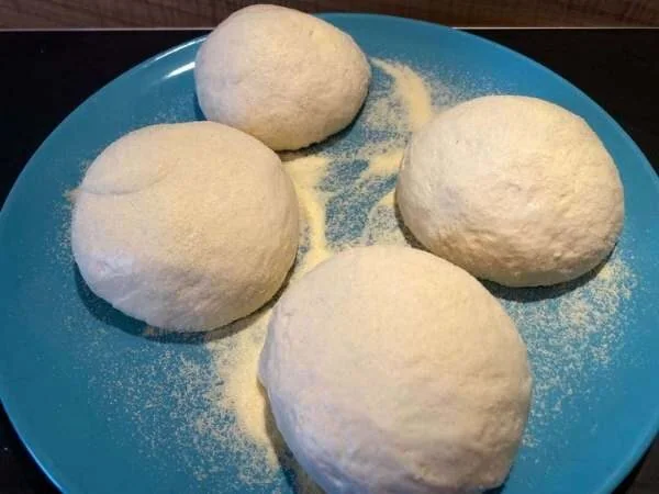 4 Pizzateige als Kugel auf einem blauen Teller