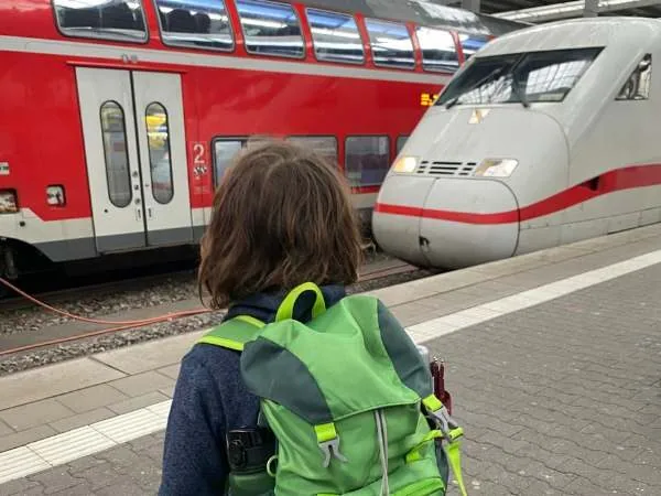 Kind am Bahnsteig mit einem Zug im Hintergrund