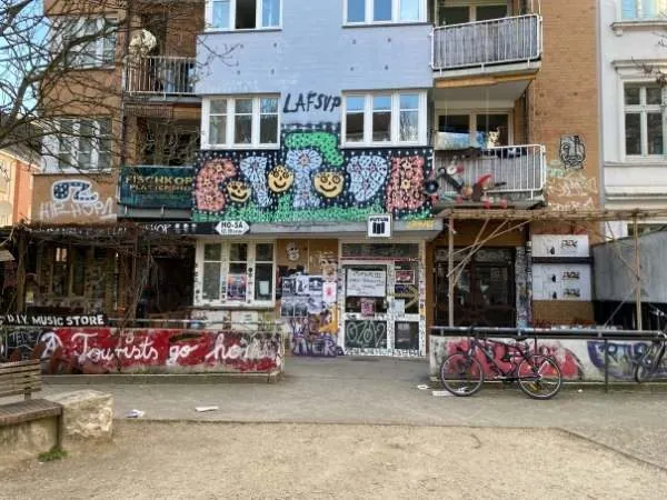 Buntes Graffiti und Street Art an einem Mehrfamilienhaus in Berlin, inklusive kreativer Wandgestaltung und Fahrrad im Vordergrund, ideal für urbane Kunst- und Lifestyle-Blogging.