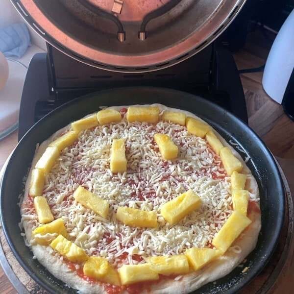 Pizza mit Ananas Gesicht im Ofen