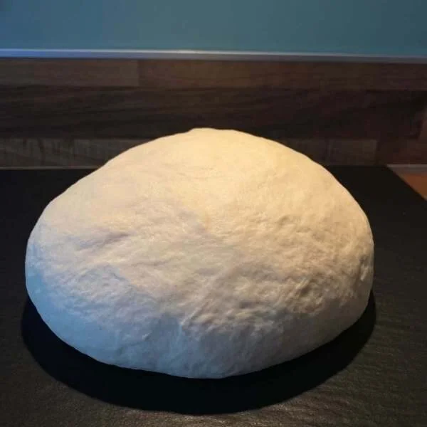 Pizzateig gewirkt auf einer Arbeitsplatte in schwarz