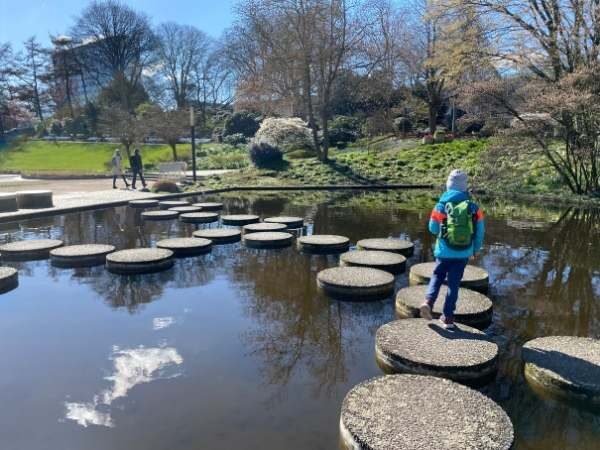 Ein Kind überquert Steine im Wasser im Park mit Natur und Entspannung.