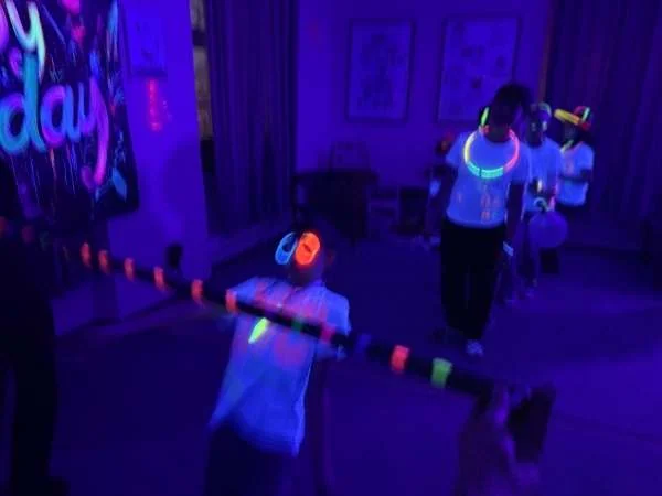 Limbo Tanz im Dunklen - 1 Kind tanzt gerade unter der Stange durch, die anderen warten dahinter.