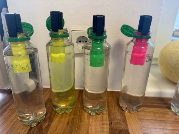 Flaschen mit Wasser und Leuchtstift dran geheftet