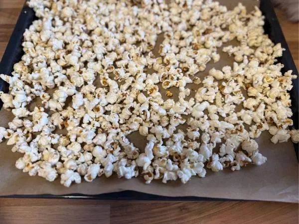 Knuspriges Popcorn, frisch und selbst gemacht, auf Backpapier ausgebreitet für einen Kinderfilmabend. Perfekt für Snacks und Familienmomente.