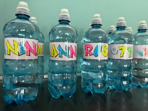 Bunte Wasserflaschen mit handgeschriebenem Namensschild f&uuml;r Kinder.