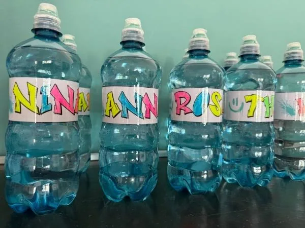 Bunte Wasserflaschen mit handgeschriebenem Namensschild für Kinder.