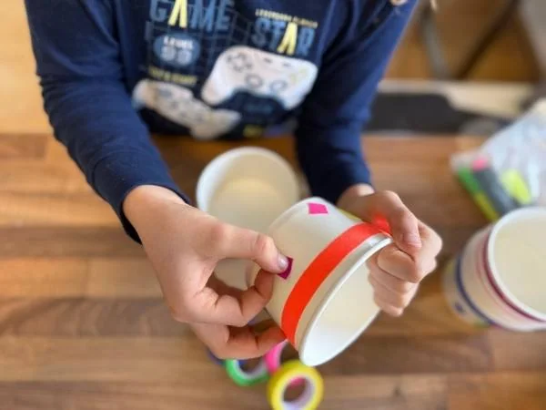 Kind, das die Snack Becher mit leuchtender Textilklebeband dekoriert
