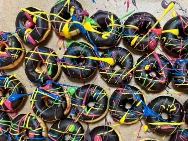 Leckere Schokoladendonuts mit buntem Zuckerguss und Zuckerspritzern, perfekt als Snack oder für Partys, optimal für Naschkatzen und Süßigkeitenliebhaber.