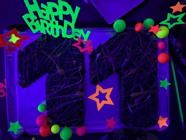Bunte Neon-Partydekoration für Geburtstag, leuchtende Bälle, Sterne und "Happy Birthday" Schriftzug für besonderen Anlass.