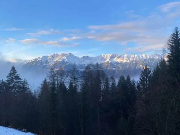 Alpenpanorama mit verschneiten Gipfeln und Tannen im Winter, ideal für Winterurlaub auf den Kanaren, um dem kalten Wetter zu entfliehen.