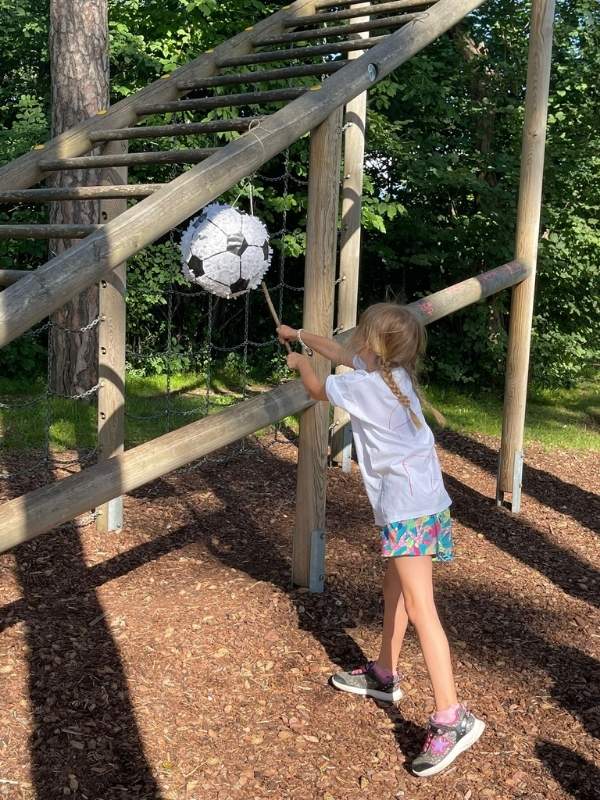 Kind schlägt auf eine Fußball Pinata mit einem Stab