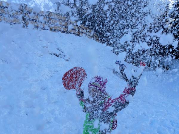 Kind das den Schnee in die Luft wirft