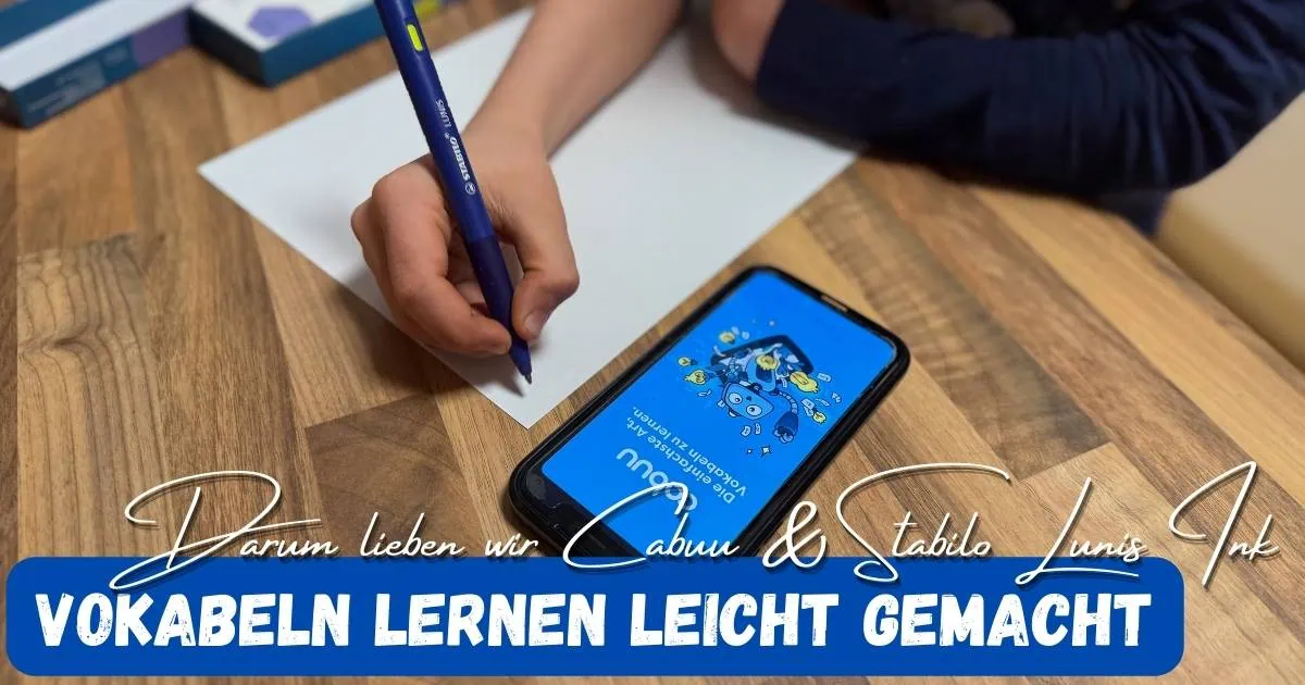 Beitragsbild mit dem Titel: Vokabeln lernen leicht gemacht - Darum lieben wir Cabuu & Stabilo Lunis Ink. Im Hintergrund sieht man eine Hand die mit dem Stift schreibt und die Cabuu App am Handy