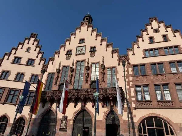 Bürgerhaus mit gotischer Architektur, Flaggen vor dem Gebäude, blauer Himmel, historische Stadtansicht in Deutschland.
