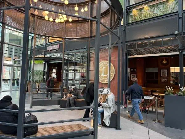Ein modernes Café im industriellen Stil mit Glaswänden, gemütlichen Sitzgelegenheiten und entspannter Atmosphäre, ideal für Kaffeepausen und Treffen in der Stadt.