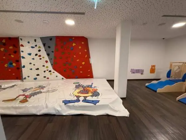 Kletterwand und Spielbereich für Kinder in einer Indoor-Spielhalle, mit bunten Kletterwänden und Rutschbahn, ideal für Kinder zum Spielen und Klettern.