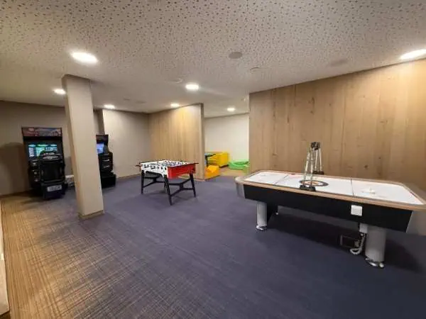 Entspannter Spielbereich für Kinder mit Tischfußball, Airhockey und Spielkonsolen in modernem, kinderfreundlichem Spielzimmer im Zugspitzresort