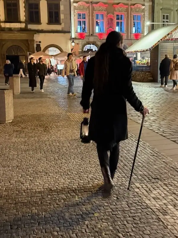 Geisterf+hrung durch Prag - hier sieht man unseren Stadtführer von hinten - auf belebter Stadtstraße in Prag bei Nacht, historische Gebäude im Hintergrund, stimmungsvolle Beleuchtung, urbanes Ambiente, Familienfreundliche Atmosphäre, Tschechische Haupts.