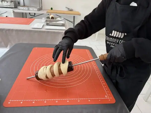 Kind beim kreativen Backen eines Trdelnik in Prag mit Kindern.