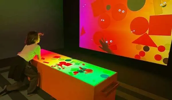 Kinder spielen an einem bunten, leuchtenden Tisch mit digitalen Figuren in einem Museum in Prag, ideal für Familienaktivitäten in der tschechischen Hauptstadt.