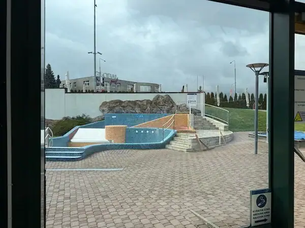 Blick durch eine Glasfassade auf den Wasserpark im Aquapalace Prag mit Kinderbecken und Wasserrutschen, ideal für Familienausflug, Erfahrungsbericht.